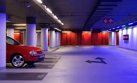 Brightly lit car park level with painted columns and direction markings after the lighting upgrade.