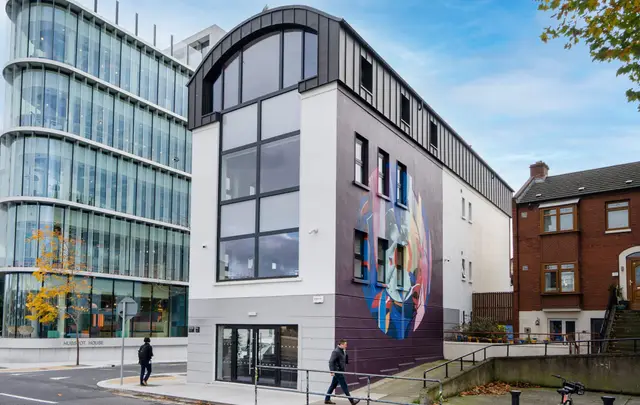 The City Quay building beside a glazed office block, with a large mural on its side wall.