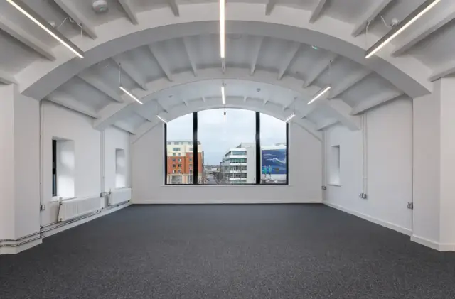 Top-floor office space under the curved roof, with linear lighting following the roof ribs.
